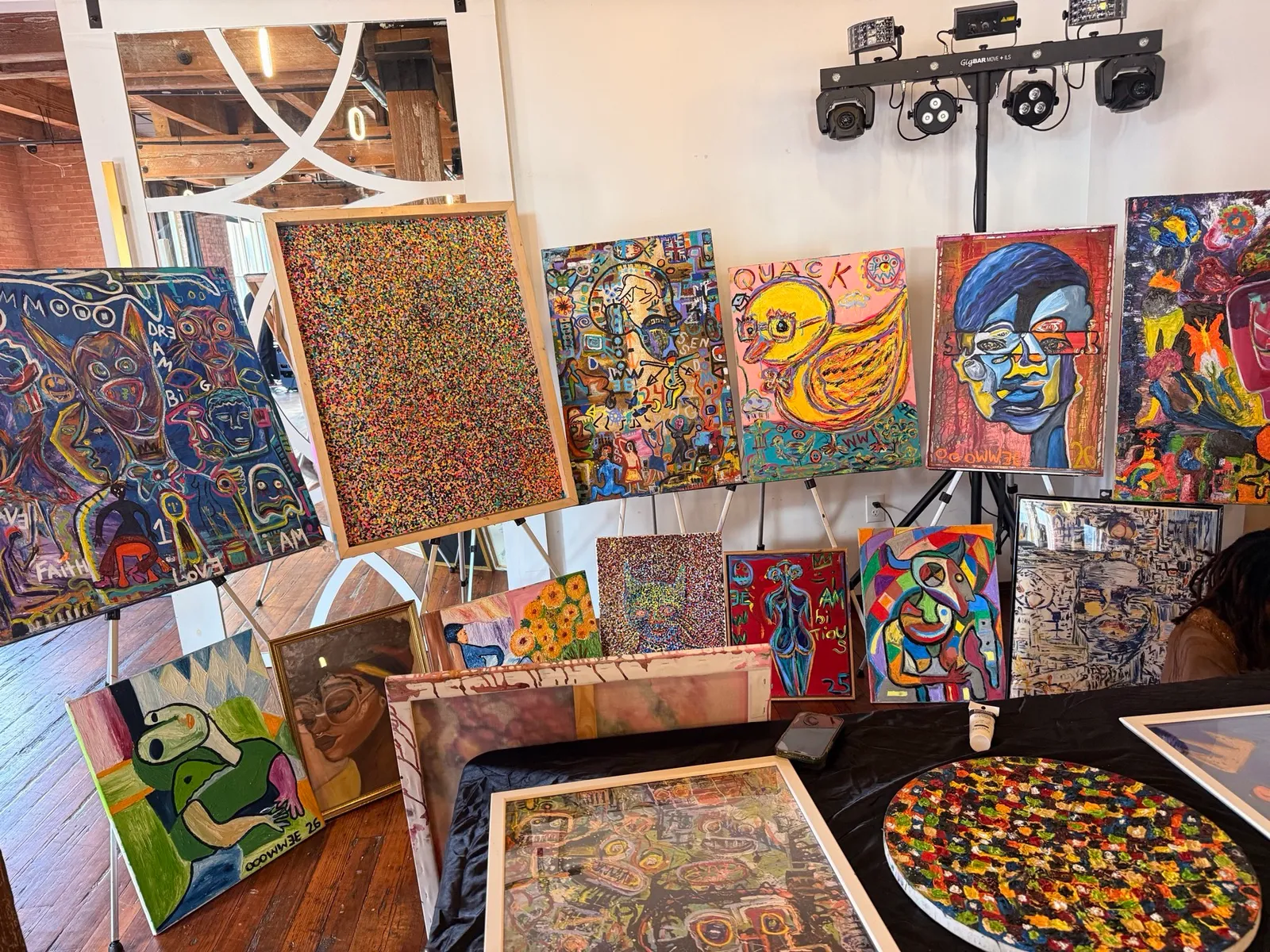 His booth at an indoor market -- easels of canvases, QUACK and the dot pieces up front